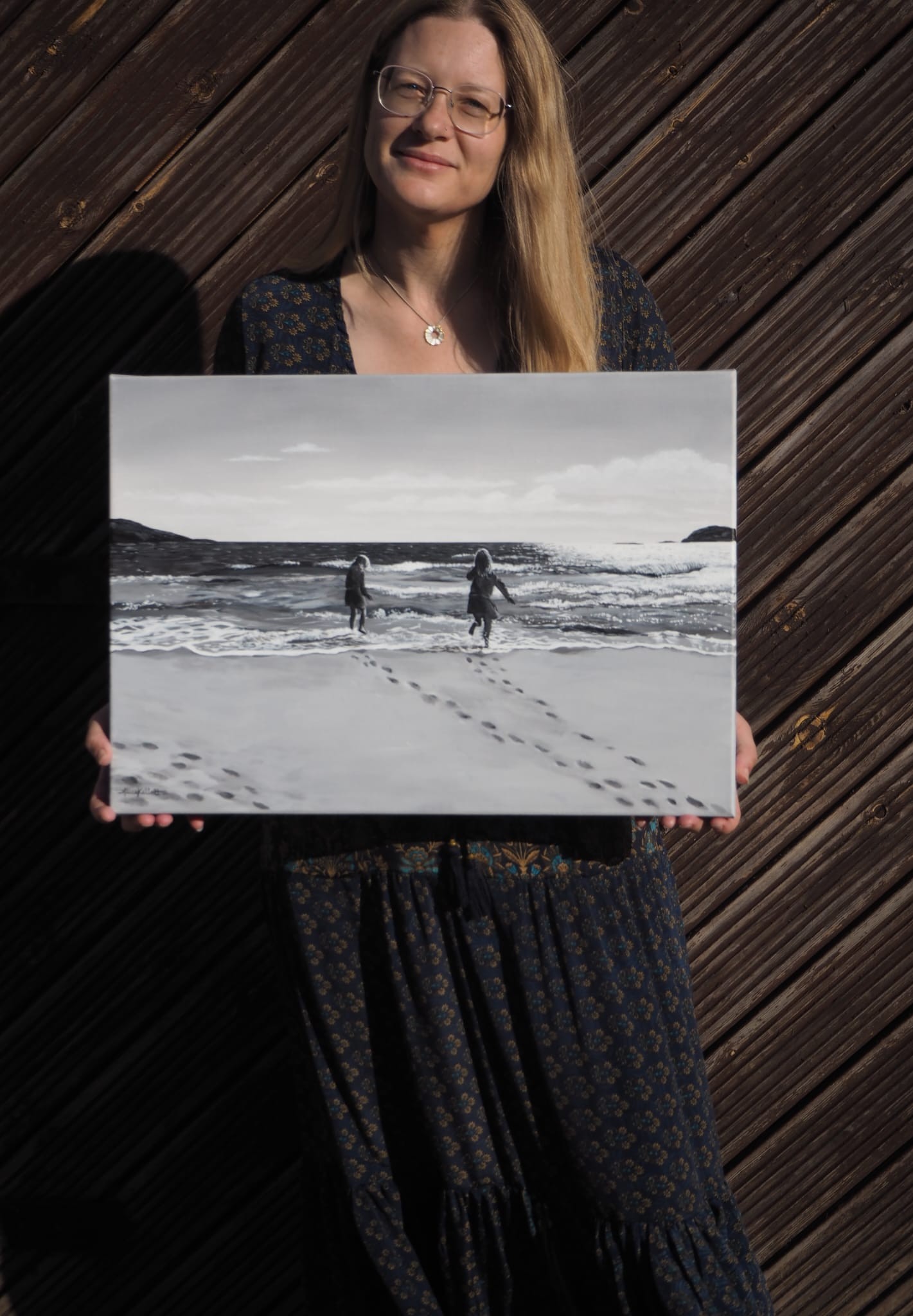 Artist holding painting of children playing on the beach